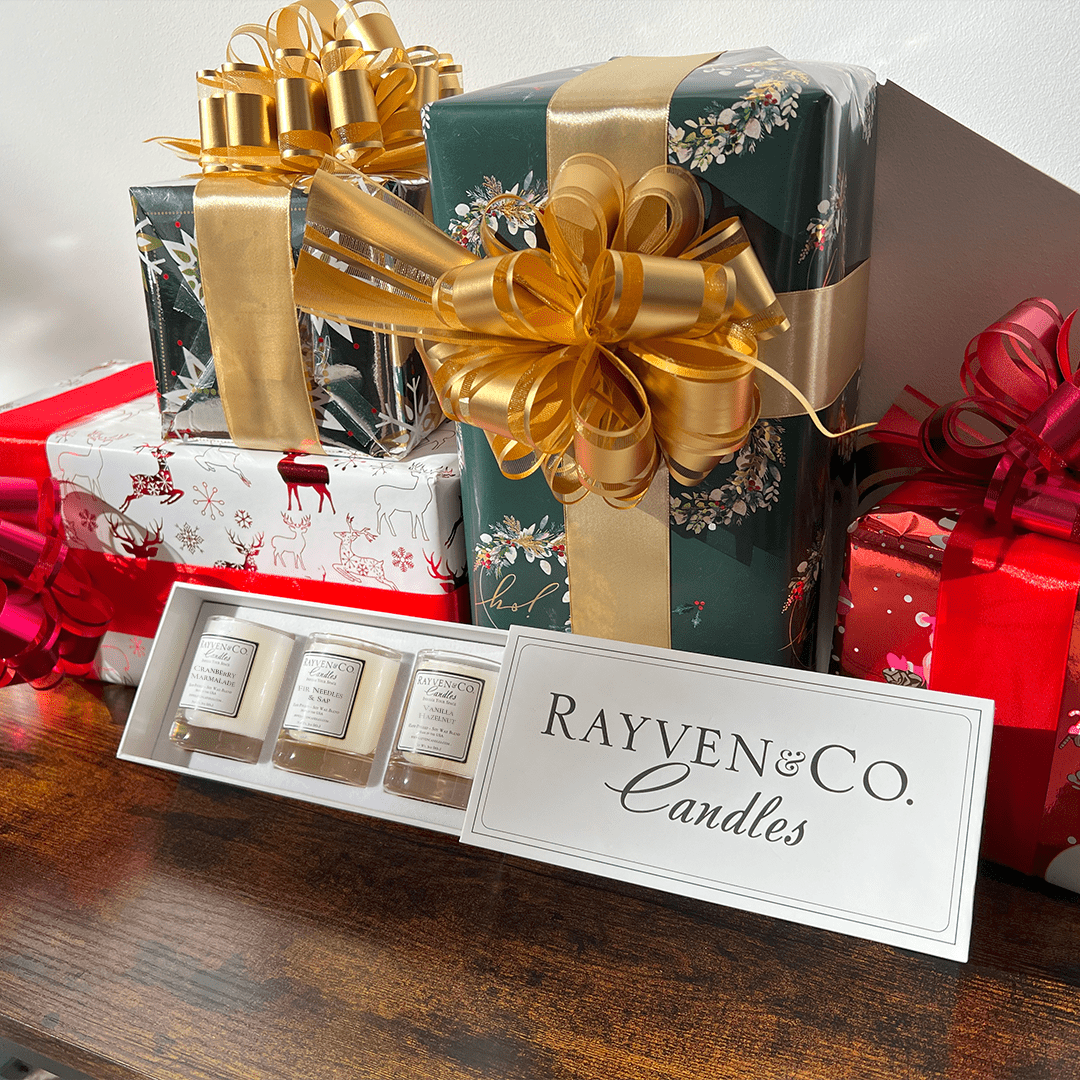 Elegant white small candle gift set from Rayven & Co. Candles in front of Christmas presents, features Cranberry Marmalade, Fir Needles & Sap, and Vanilla Hazelnut.